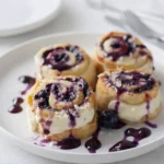 Blueberry Cheesecake Rolls fresh out of the oven, topped with powdered sugar"