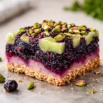 Blackberry Pistachio Dream Bars stacked on a wooden board