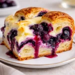 Golden brown Blueberry Cream Cheese Croissant Casserole in a white dish.