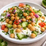 A vibrant Cottage Cheese and Chickpeas Salad in a white bowl on a marble counter.