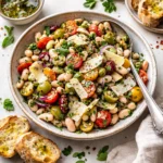 Italian White Bean Salad in a white bowl with cherry tomatoes and olives.