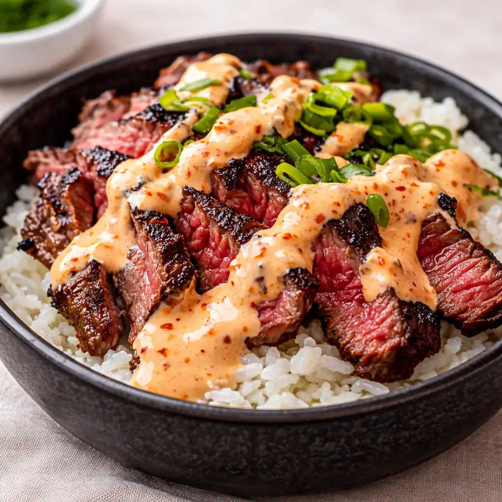 Korean BBQ Steak Rice Bowls with Spicy Cream Sauce served in a ceramic bowl on a wooden table.