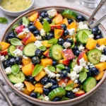 A vibrant Blueberry Peach Feta Salad in a white serving bowl with fresh basil.