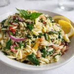 Delicious Lemon Basil Orzo Pasta Salad in a white bowl on a wooden table.