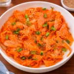 Fresh Raw Carrot Salad with sesame seeds and green onions in a white bowl.
