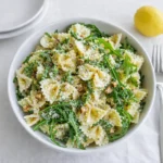 A bowl of Refreshing Lemon Arugula Pasta Salad with tomatoes and parmesan.